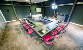 a large conference room with multiple tables , chairs , and a computer monitor , all set up for a meeting at Leonardo Hotel Almere City Center
