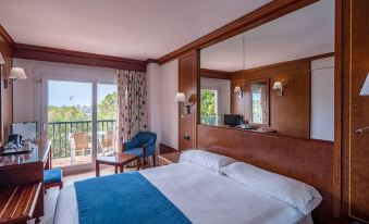 a bedroom with a large bed , blue blanket , and wooden headboard next to a balcony at THB Felip - Adults Only
