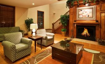 a cozy living room with a fireplace , comfortable seating , and a wooden floor , decorated with plants and flowers at Holiday Inn & Suites Dallas-Addison