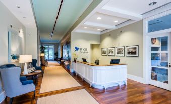 a modern office building with wooden floors , white walls , and blue ceiling lights , as well as a reception area with a white desk and chairs at WaterSound Inn