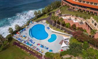 an aerial view of a resort with a large pool surrounded by lounge chairs and umbrellas at Monte Mar Palace Hotel