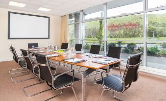 a conference room with a long table , chairs , and a screen , set up for a meeting at Harbour Hotel
