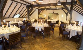 a large dining room with wooden floors and tables covered in white tablecloths and chairs at Fletcher Hotel-Restaurant de Klepperman