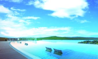 a large outdoor swimming pool surrounded by grass , with several lounge chairs placed around it at New Akan Hotel