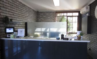 a room with a brick wall and a white window , where an office desk is set up at The Heritage Bendigo