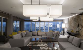 a modern living room with a gray couch , black and white patterned rug , and large windows at Simon Hotel