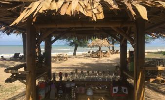 a beach scene with a wooden gazebo and the ocean in the background , surrounded by trees at Ao Thai Resort