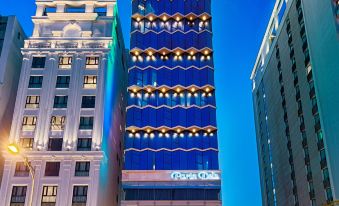 a tall building with blue and white lights is shown in the city at night at Paris Deli Danang Beach Hotel