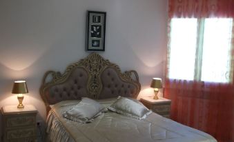 a well - decorated bedroom with a large bed , two nightstands , and a window with red curtains at Rahma