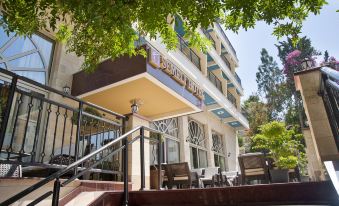 a large building with a staircase leading up to it , surrounded by trees and bushes at Semeli Hotel