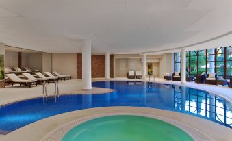 an indoor swimming pool with a large hot tub in the middle , surrounded by lounge chairs at Sheraton Mallorca Arabella Golf Hotel
