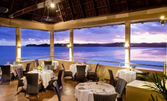 a restaurant with white tablecloths and chairs is shown with a view of the ocean at Shangri-La Yanuca Island, Fiji