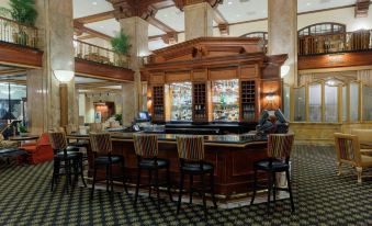 a large , well - lit room with wooden paneling and a bar counter , surrounded by chairs and tables at Peabody Memphis