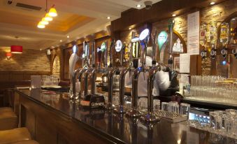 a bar with multiple beer taps , as well as a bartender behind the counter preparing drinks at An Grianan Hotel
