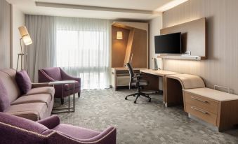 a modern hotel room with a large window , comfortable seating , and a desk area equipped with a computer and phone at Courtyard Omaha Bellevue at Beardmore Event Center