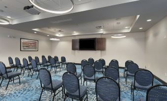 a conference room with rows of chairs arranged in a semicircle , and a television mounted on the wall at Holiday Inn & Suites Arden - Asheville Airport