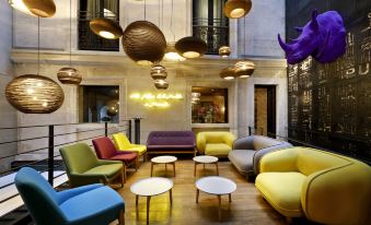 a modern hotel lobby with colorful seating , a bar , and hanging lights , creating a vibrant atmosphere at Hotel the Public - Special Category