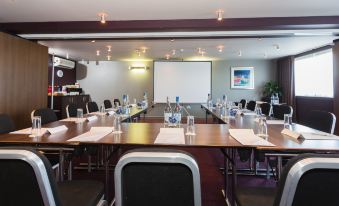 a conference room set up for a meeting , with multiple chairs arranged in a semicircle around a long table at Holiday Inn Aberdeen - West