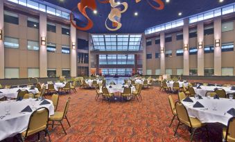 a large banquet hall with multiple tables and chairs arranged for a formal event , possibly a wedding reception at Holiday Inn Manitowoc