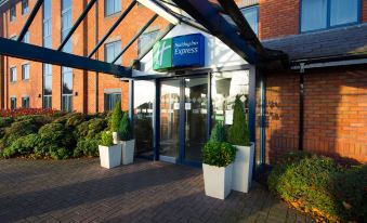 "a modern hotel entrance with a glass door , brick walls , and blue signage for "" holiday inn express ""." at Holiday Inn Express Stafford