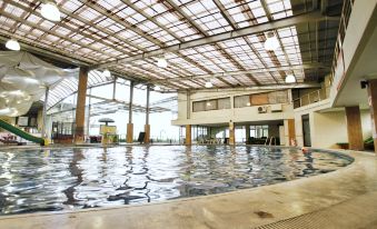 an indoor swimming pool with a large glass roof , allowing natural light to illuminate the space at Hotel Cianjur Cipanas