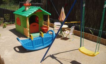 a wooden playhouse with a blue boat on it , surrounded by various toys and play equipment at La Casa Verde