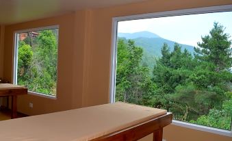 The bedroom has large windows that overlook the mountains, and there is an unmade bed in front of them at Haatiban Resort