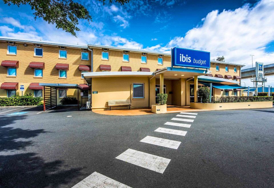 "a large , yellow building with a blue sign that says "" ibis budget "" in front of it" at Ibis Budget Brisbane Airport