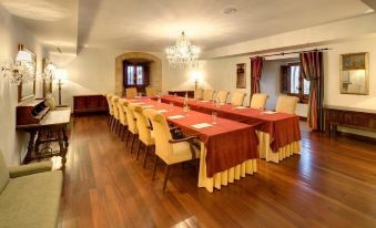 a large conference room with wooden floors and a long table covered in a red tablecloth at Parador de Leon - San Marcos