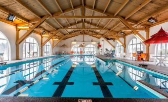 an indoor swimming pool with a wooden ceiling and large windows , providing natural light at The Aurora Inn Hotel and Event Center