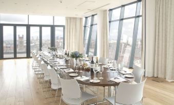 a long dining table set up for a formal event , with white chairs arranged around it at Hope Street Hotel