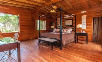 a cozy bedroom with a wooden floor and a canopy bed in the middle of the room at Dream Valley Belize