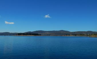 a serene lake with a mountainous landscape in the background and a clear blue sky above at Discovery Parks - Jindabyne