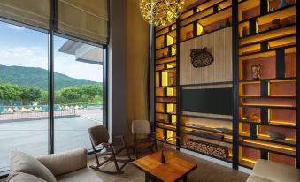 a cozy living room with a wooden coffee table and a flat - screen tv mounted on the wall at Dusitd2 Khao Yai