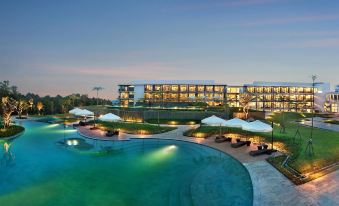 a large hotel with a swimming pool surrounded by chairs and umbrellas , creating a relaxing atmosphere at Royal Tulip Golf Resort Gunung Geulis