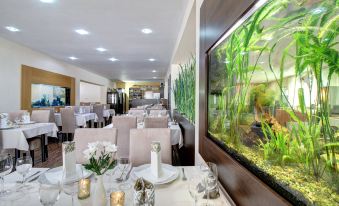 a dining room with tables and chairs set up for a meal , along with a large fish tank in the background at Hotel Dixon