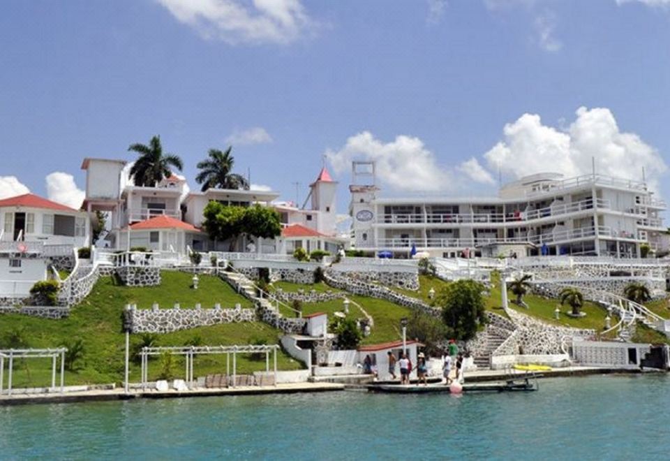 a large white building situated on the side of a body of water , with a dock extending into the water at Hotel Laguna Bacalar