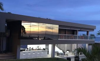 a modern house with a large glass window and balcony , overlooking a beautiful sunset over the ocean at Acantilados
