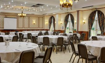 a large , well - lit dining room with multiple round tables and chairs arranged for a formal event at Quorn Country Hotel