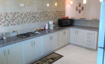 a kitchen with white cabinets , a black oven and microwave , and a rug on the floor at Rahma