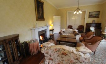 a cozy living room with a fireplace , multiple couches , and a painting on the wall at Glengarry Castle Hotel