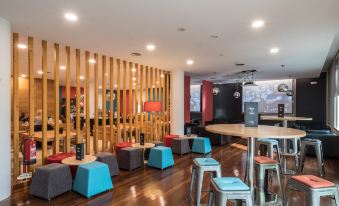 a modern lounge area with wooden floors , blue and red chairs , and a bar counter at Stay Hotel Guimarães Centro