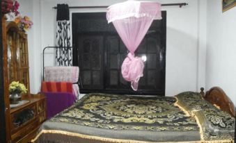 a room with a large bed and a pink umbrella hanging from the ceiling , creating a cozy atmosphere at White Home