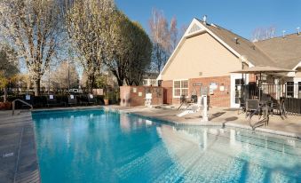 a large swimming pool with a house in the background and several lounge chairs around it at Residence Inn Stockton