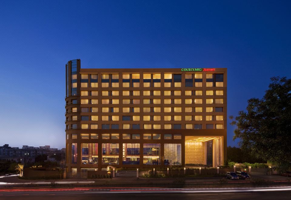 a large hotel building with a modern design and green lights is lit up at night at Courtyard Ahmedabad