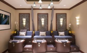 a modern spa with three blue couches , two of which are located under hanging lights , and three square - shaped tables at The Ritz-Carlton, Marina del Rey