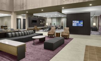 a modern living room with various seating options , including couches , chairs , and a coffee table at Courtyard Dallas Flower Mound