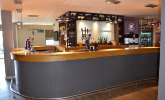a modern bar with a wooden counter and black and white shelves filled with various bottles at Dublin Airport