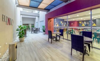 an indoor dining area with wooden flooring , chairs , and tables , as well as potted plants and a sliding glass door at Novus Plaza Hodelpa