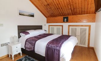 a large bed with a purple blanket is in a room with wooden walls and ceiling at Moon Face